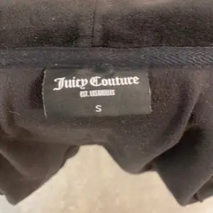 En juicy couture kofta som är helt svart. Ända nackdelen är att en av metall bitarna på snöret är av och därför säljs den för ett mycket lägre pris