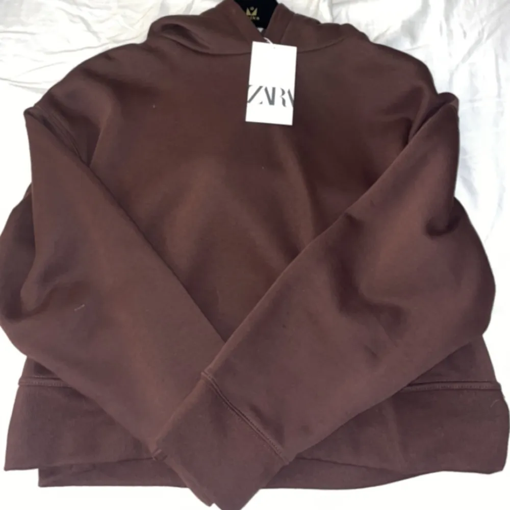 En mörkbrun hoodie från zara med slit på sidorna som är helt oanvänd. Det är strl L men är lite liten i storleken . Tröjor & Koftor.