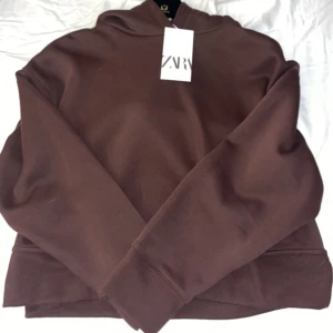 Hoodie  - En mörkbrun hoodie från zara med slit på sidorna som är helt oanvänd. Det är strl L men är lite liten i storleken 