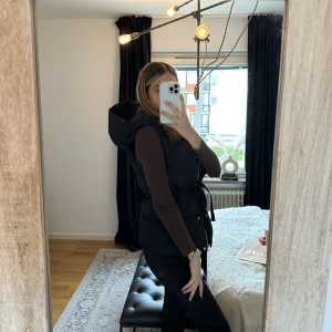 Väst  - Svart Väst med luva och knytning. Storlek XS-S