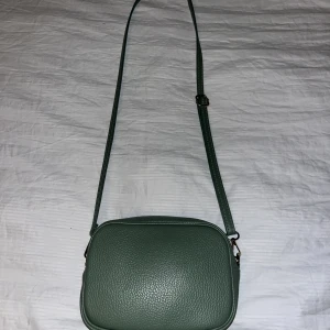 Grön väska - Fin grön axelväska. Liten del har gått av på dragkedjan men den funkar lika bra ändå.