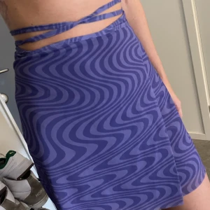 Omlottkjol med lila mönster  - Kjol från Weekday med band som du kan knyta på olika sätt. Använd en gång. 