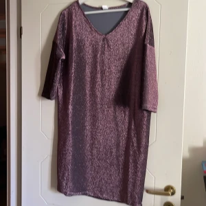 Glittrig klänning - Lilaglittrig kort klänning med v-ringad hals. Lätt oversize. Halvlånga ärmar Aldrig använd