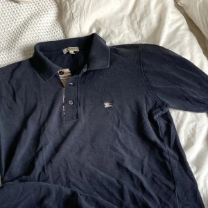Burberry piké - Burberry pikétröja slim fit, väldigt bra skick, köpt second hand men knappt använd av mig. Gjord i Storbritannien, 100% bomull, mörkblå