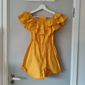 Jumpsuit  - Jumpsuit som kan användas som off shoulder. Volang upptill och band i midjan. Knappt använd 