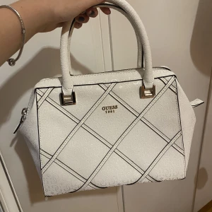 Guess väska - Vit handväska från guess i nyskick, längre band och påsen följer med! Säljs pga att den inte används