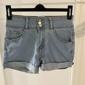 Ljusblå Jeans Shorts - Så söta ljusblå jeans shorts. Dem är storlek 36/S och formar kroppen så snyggt. Dem 3 knapparna är en superfin detalj. Köpta på Shein för två år sedan men aldrig använda då det är fel storlek. Så snygga inför sommaren och säljer de billigt💕