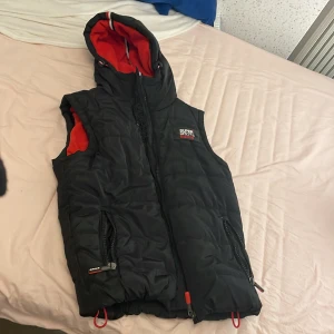 Superdry dun vest - Köpte västen på erikshjälpen nåt år sedan. Har bara använt den några enstaka gången. Den har gummiband i midjan och i luvan så man kan göra den tajtare och dragkedjor på fickorna. Och en inner ficka