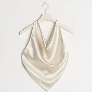 Till nyårsfesten!  Draped top with a halterneck design. The top is perfect for the party, beige and sleeveless. It has satin material, a cropped length, open back and self-tie at the back.