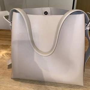 Beige väska från mango - Beige superfin väska från mango. Inköpt nyligen för 599 kr och har enbart använt den ett fåtal gånger. Hörnen är lita avskavda och det finns några små svarta märken på väskan som ses på mittenbilden. Därav priset!