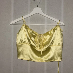 Topp  - Gul topp med knyte i axlarna och bröstet. Använd en gång 