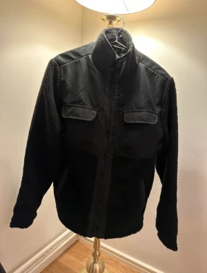 Saligia lager157 pilejacka - Jacka i pile med vävd kvalitet på bröstet. Ståkrage och dragkedja fram. Bröstfickor och snedställd stolpficka i var sida samt en innerficka.  Ny, bara testad