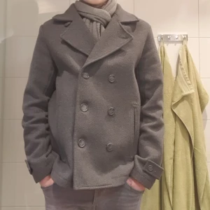 Kort rock - Tja säljer denna grå rocken. Den är perfekt nu till vintern. Skick 9/10 inga skavanker. Nypris ca 1000 kr. Han på bilderna är 178  väger 65 kg och brukar ha på sig s/m. Skulle säga den passar de flästa över 180 då den är lite stor i storleken.