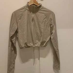 Croppad långärmad tröja ICIW - Beige långärmad tröja från icaniwill i ”croppad” modell som går att dra åt nedtill. Använd endast ett par gånger.