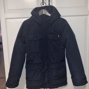 Vinterjacka från Lyle & Scott - Jättefin marinblå jacka i absolut nyskick. Sonen växte ur den på en gång. Storlek 14-15 år (som en xs.) 300:- + frakt. 