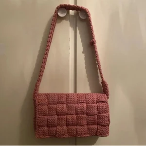 Virkad väska - Virkad väska i rosa gjord efter inspiration av Bottega Venettas Casette väska. Väskan är rymlig och har ett eget handtag. längd: 30cm höjd: 16cm bredd:6cm Pris: 900kr+porto OBS! Katter finns i hushållet