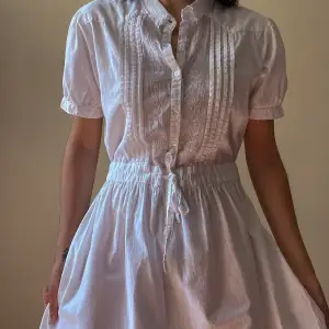 This is a sweet vintage cotton dress with unique details.  Decorated frontal panels with buttons & pleating and an embroidered floral collar. Lightly Puffed Sleeve and a Drawstring waist. 2 Pockets  112 CM Length 21 CM Sleeve 38 CM Shoulder 80 CM Chest