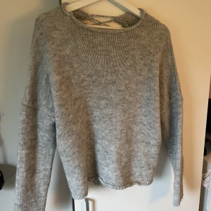 Grå stickad tröja - Har en snörning längst hela ryggraden, skitsnygg! 