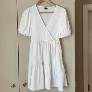 Studentklänning med puffärm - Vit kort klänning med puffärmar och knytning i sidan från Gina Tricot.  Använd en gång. Perfekt till student och avslutningar💗  Storlek S