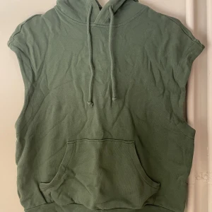 Armlös Collegetröja - En armlös grön huvtröja från H&M, använd men inga defekter. Storlek S.