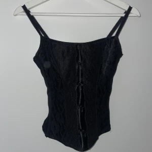 Svart korsett i spets - En svart korsett med spets framtill och spännen baktill. Helt omöjlig att ta bild på men den är jättefin lol
