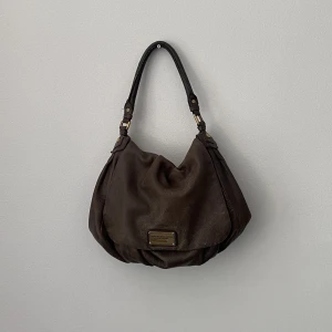 Marc Jacobs Väska - Jättefin Marc Jacobs väska. Lite sliten och har två fläckar på baksidan (se bild 3), däremot inget som syns när man bär väskan då det inte är på framsidan.  Lång axelrem medföljer även.🫶🏻✨ 