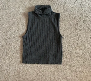 Grå topp - Jättefint linne med polokrage och snygg ”lettuce hem” runt kanterna, från BikBok 💗 Mörkgrå och funkar året runt:) 