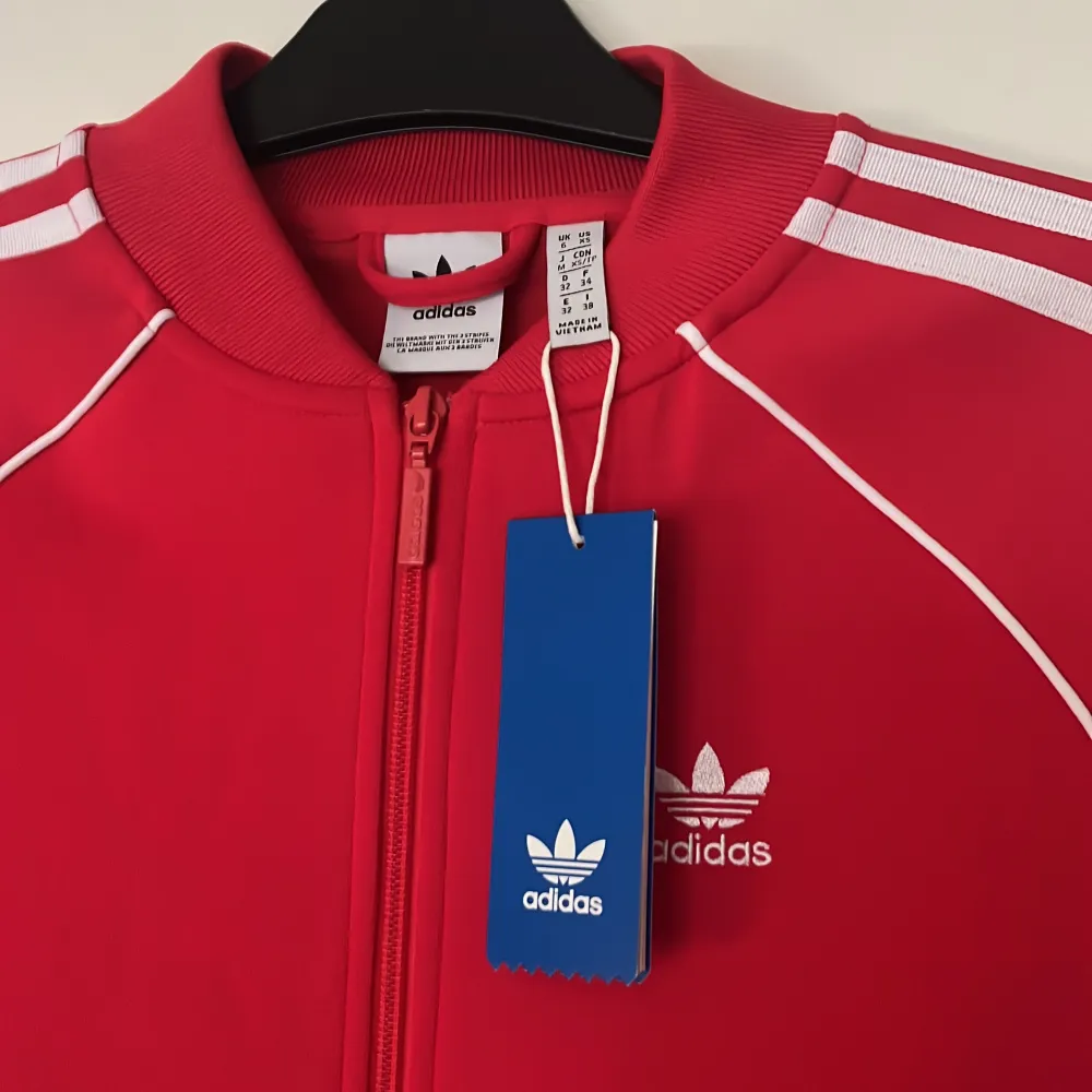 Röd adidas kofta köpt på Zalando i strl 32 men passar även 34 alla lappar är kvar då den aldrig är använd. Hoodies.