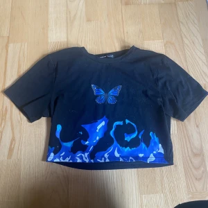 Svart topp - Svart topp med blått fjäril tryck från Shein. Är lite knottrig men annars i bra skick.