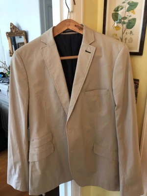 Fräsch sommarkavaj - Fin sommarkavaj, ljusbeige.  Knappt använd. Storlek 54. Slim fit.  2 knappar framtill och vid ärmslut. Finns i Fredhäll, Stockholm för hämtning.
