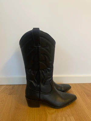 Svarta Cowboy Boots från Stradivarius  - Säljer mina svarta fina cowboy boots i konstläder från Stradivarius, skorna är använda vid ett tillfälle och säljs pga att jag köpt ett par i en annan färg. Väldigt bekväma och i mycket fint skick! Nypris 700kr 