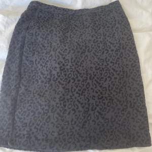 Svart, tight kjol med ett diskret leopardmönster och dragkedja där bak  Strl. Xs Nypris: 300kr  Köpt i någon butik - märke: peppercorn