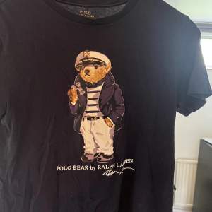 Mörkblå Ralph lauren t-shirt med en Björn på! Tröjan har används i ca ett år och skicket är 7,5/10 då den inte har några synliga defekter men har använts! Storleken är xs!😀nypris: 529 kr