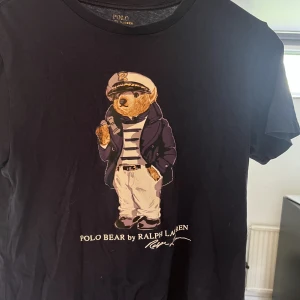 Ralph lauren T-shirt - Mörkblå Ralph lauren t-shirt med en Björn på! Tröjan har används i ca ett år och skicket är 7,5/10 då den inte har några synliga defekter men har använts! Storleken är xs!😀nypris: 529 kr