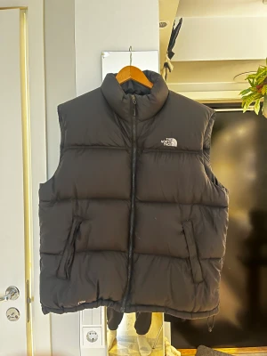The North Face Väst - Herrstorlek XL, ganska lång. Finns dragsko på sidorna så man kan anpassa passformen själv. Innerficka på vänster sida som är rätt djup. Använd fåtal gånger, inga skavanker. Nypris 2699kr så säljer för 1500kr. Kan skickas, köparen står för frakt.