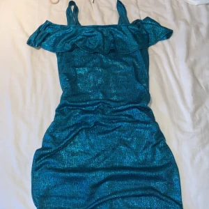 Kläning - Glitter blå/grön/turkos kläning bild 2 är mest tydlig. Mjukt lager under. Finns Axel band men man kan vika ner och ha off-shoulder se bild. Ja 