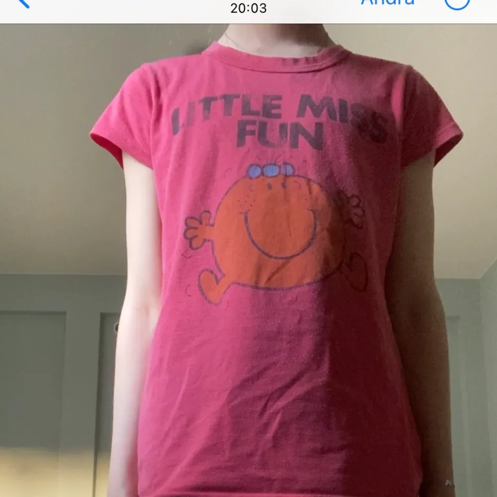 En röd T-shirt med ett liten glatt ansikte på och en text ovanför ”little miss fun”. T-shirts.