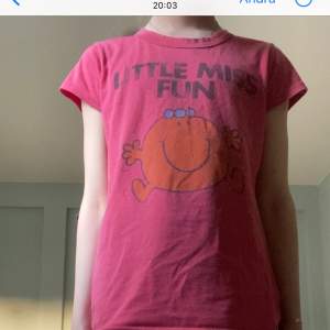 En röd T-shirt med ett liten glatt ansikte på och en text ovanför ”little miss fun”
