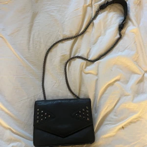 Väska  - Väska med silver detaljer går att ha cross body även över axeln. Lite sliten på sidorna. Har två fack inne med dragkedja.