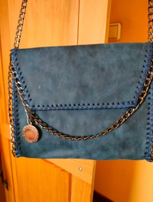 Stella McCartney väska  - Väldigt fin och välgjord väska i blått syntetiskt läder och bronsfärgad kedja. Har inget intyg så troligen kopia. 