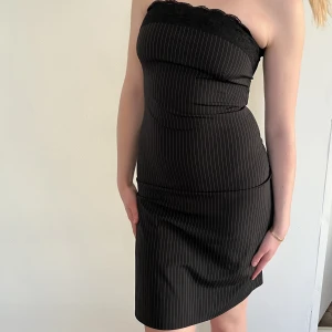 Tubklänning - Svart kritrandig tubklänning med spetsdetalj upptill. Vintage, från Kookai. Storlek 38. Fint skick, inga defekter.