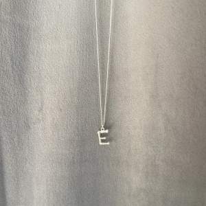 Ett snyggt silvrigt bokstavshalsband med bokstaven E som liknar Maria Nilsdotter💞 Säljer då jag inte vill ha silver smycken längre. Köpt för 299 (doppat i äkta silver)💞 