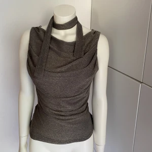 Grå skimrig topp - Grå/brun skimrig topp i Storlek S/M. Passar till festligare event och tillställningar. Med medföljande band som man kan knyta hur man vill. 🩶