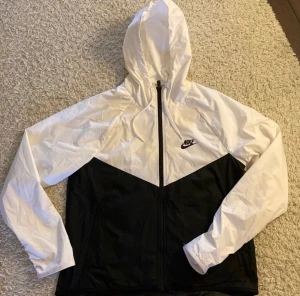 Nike vindjacka i nyskick! - Svart och vit vindjacka från Nike! Använd några gånger men i fint skick! Storlek s dam. Kan även passa storlek M