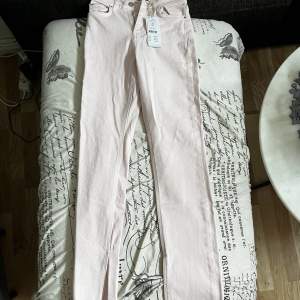 Högmidjade Ljusrosa jeans med slits i storlek 34 från Gina. Aldrig använda. 