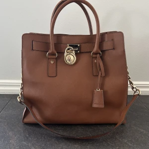 Hamilton väska - MK Hamilton i läder. Mycket fint skick den är välvårdad och lite använd. Plånbok i mycket fint skick finns till.