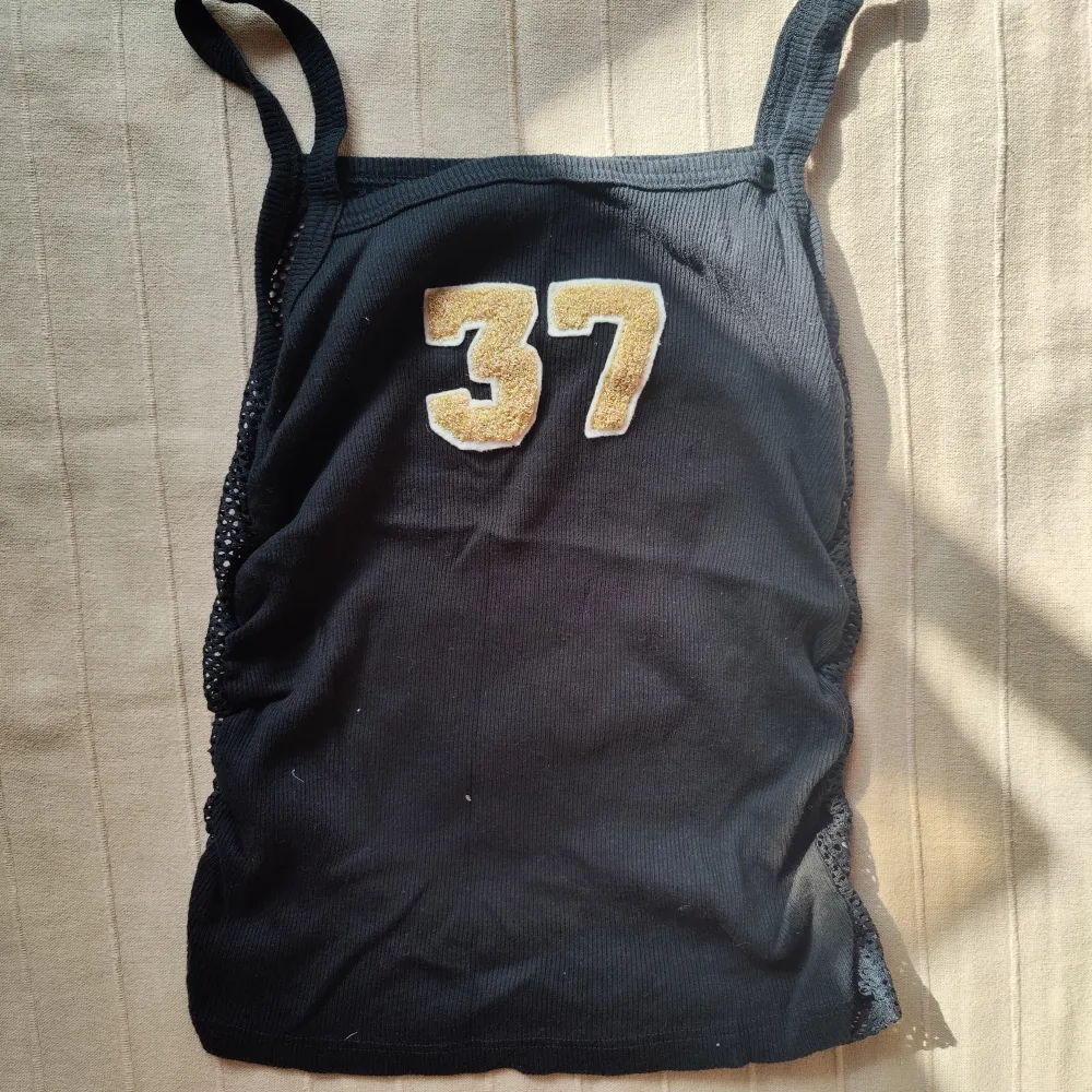 Sportigt svart linne från tidigt 2000-tal, hålstickat/ fisknät i ryggen, perfekt skick 💞. Toppar.
