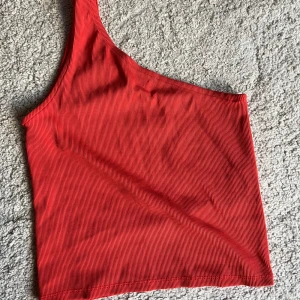 Röd topp - Röd topp med en ”ärm”. Storlek S 