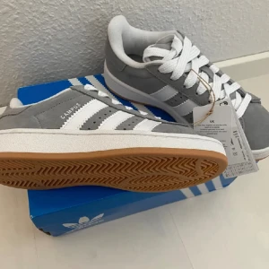 Nya Adidas Campus 00s -storlek 36 - Adidas Originals Campus 00 s j Storlek: 36 Färg: Grå (Grey Three / Cloud White / Cloud White) Ingår både vita och gråa skosnören.  Nya och oanvända. Ligger kvar i kartong. 