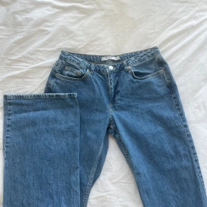 Na-kd lågmidjade jeans - Populära lågmidjade blåa jeans med vida ben från Na-Kd i storlek 36. Endast använda 2 gånger då jag inte tycker dem passar mig så bra. Helt utan anmärkningar. Ordinarie pris 699 kr